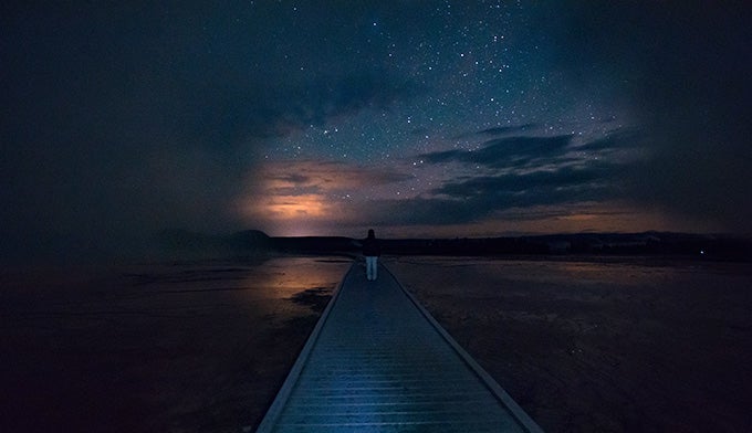 YS-night-skies-boardwalk_BreannaKellerPhotography_680 A park visitor stands in awe of the stars on the Grand Prismatic boardwalk in Yellowstone.