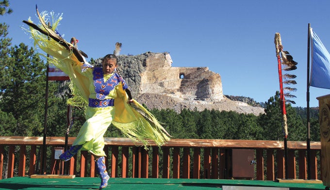 yellowstone-crazy-horse-memorial A Native American dancer with a view of Crazy Horse Memorial in the background. Courtesy Crazy Horse Memorial Foundation