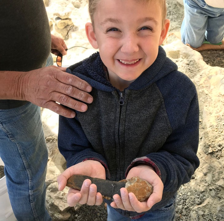 A kid grins as he holds a dinosaur fossil at a Dig for a Day event at the Wyoming Dinosaur Center in Thermopolis