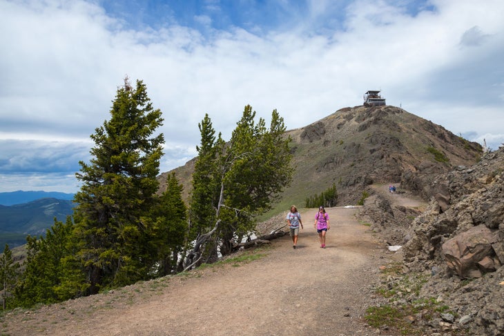 Hikers on Mount Washburn Trail near the summit with a view of the fire lookout
